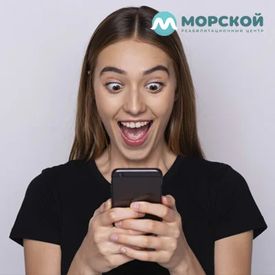 девушка с безумным выражением лица держит в руках мобильный телефон